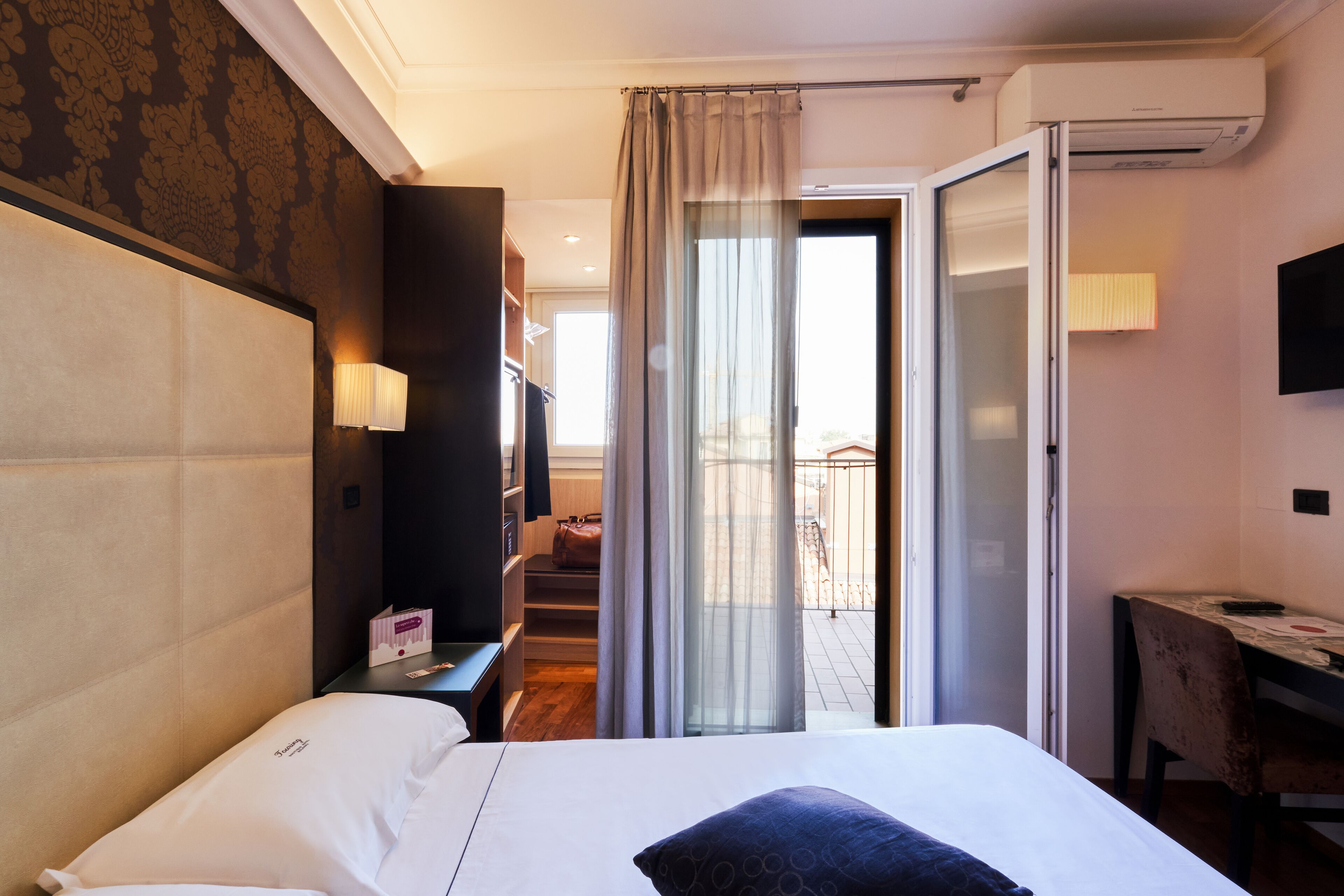 Habitación de hotel con una cama grande, un escritorio, una silla, un televisor y un balcón con vistas.