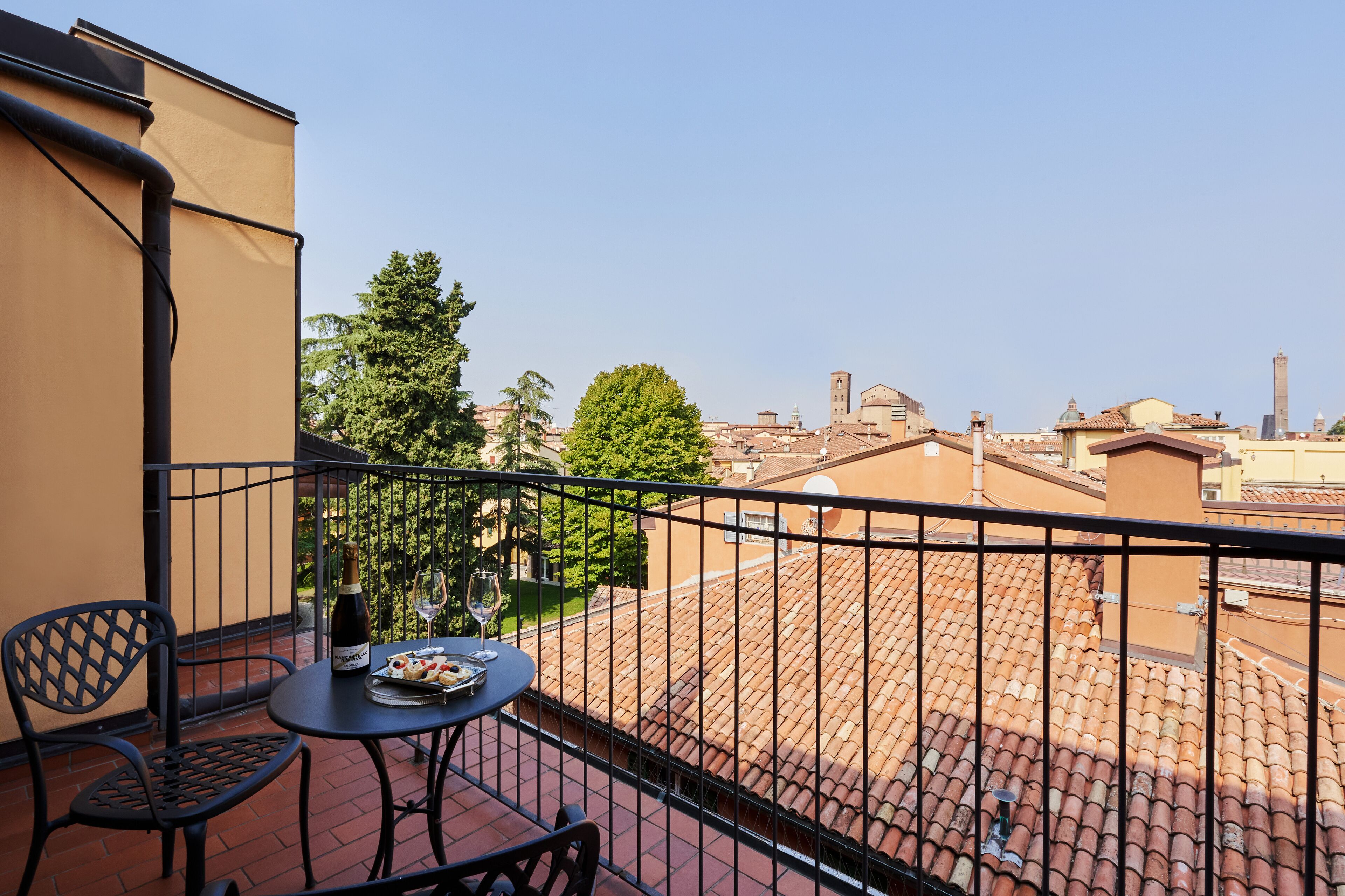 Un balcon avec une table, des chaises et une bouteille de vin.