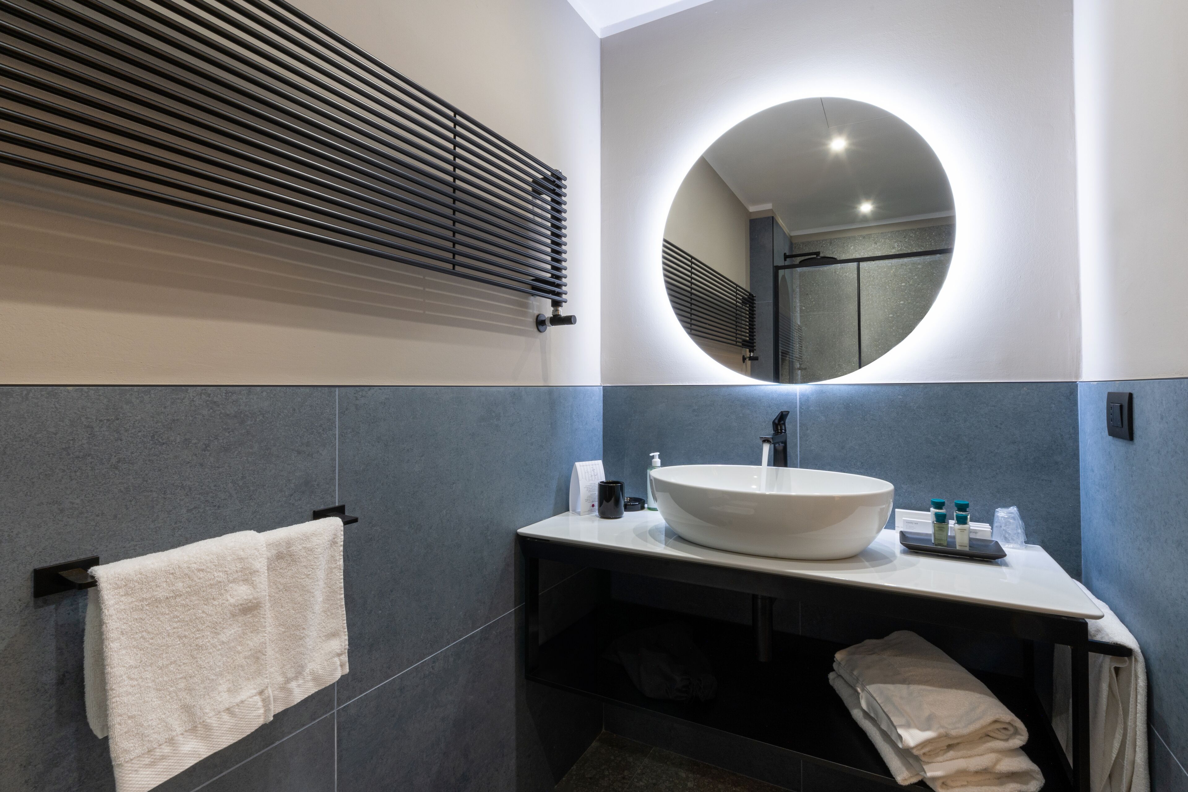 A modern bathroom with a large sink, a towel rack, and a mirror.
