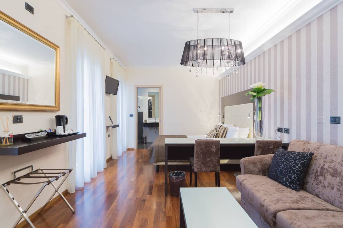 A modern living room with a sofa, a dining table, and a kitchen area in the background.