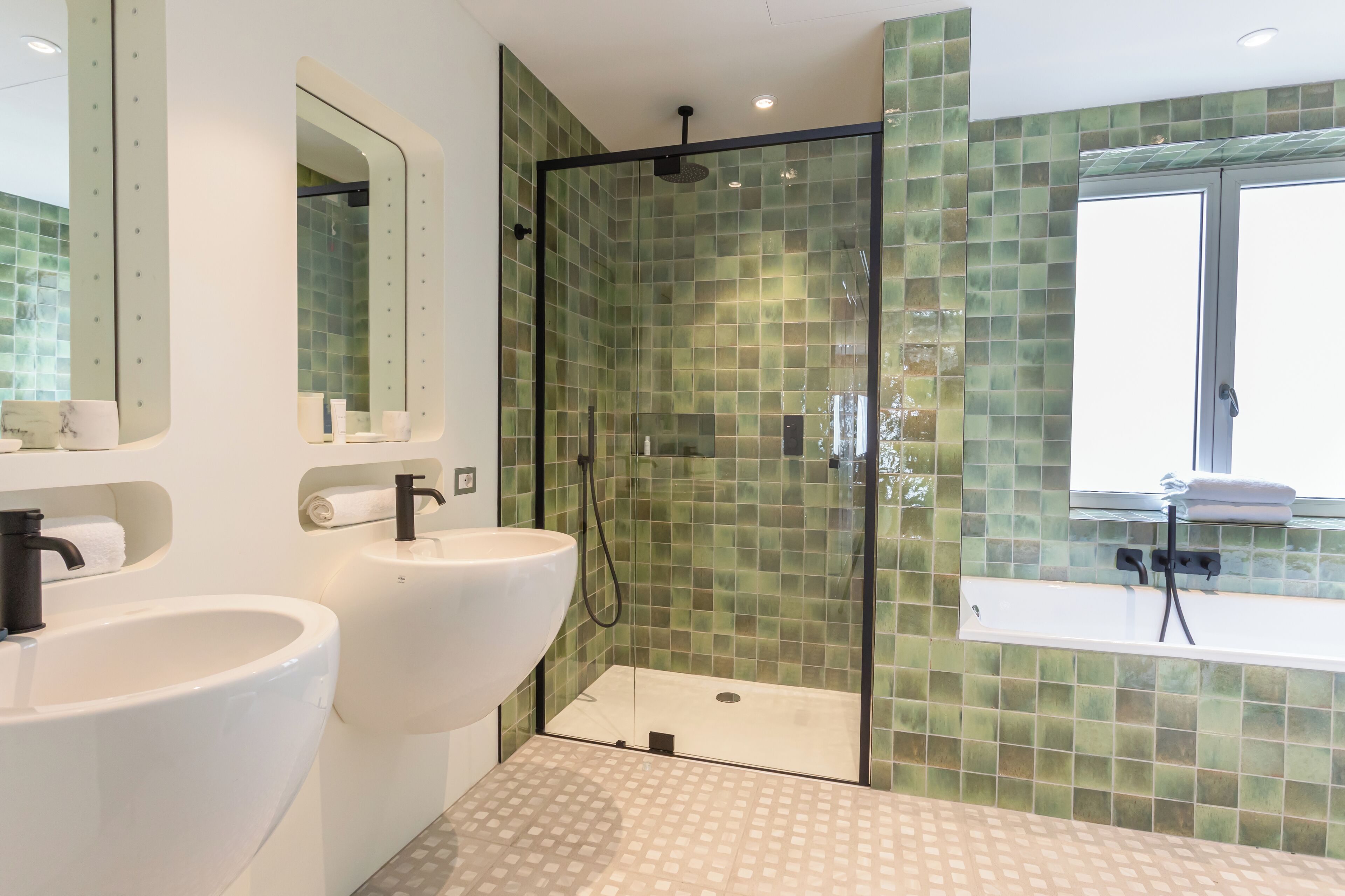 Un bagno con due lavandini, una doccia e una finestra.