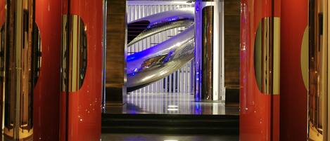 A modern interior with metallic and red accents, featuring a reflective floor and a central illuminated structure.