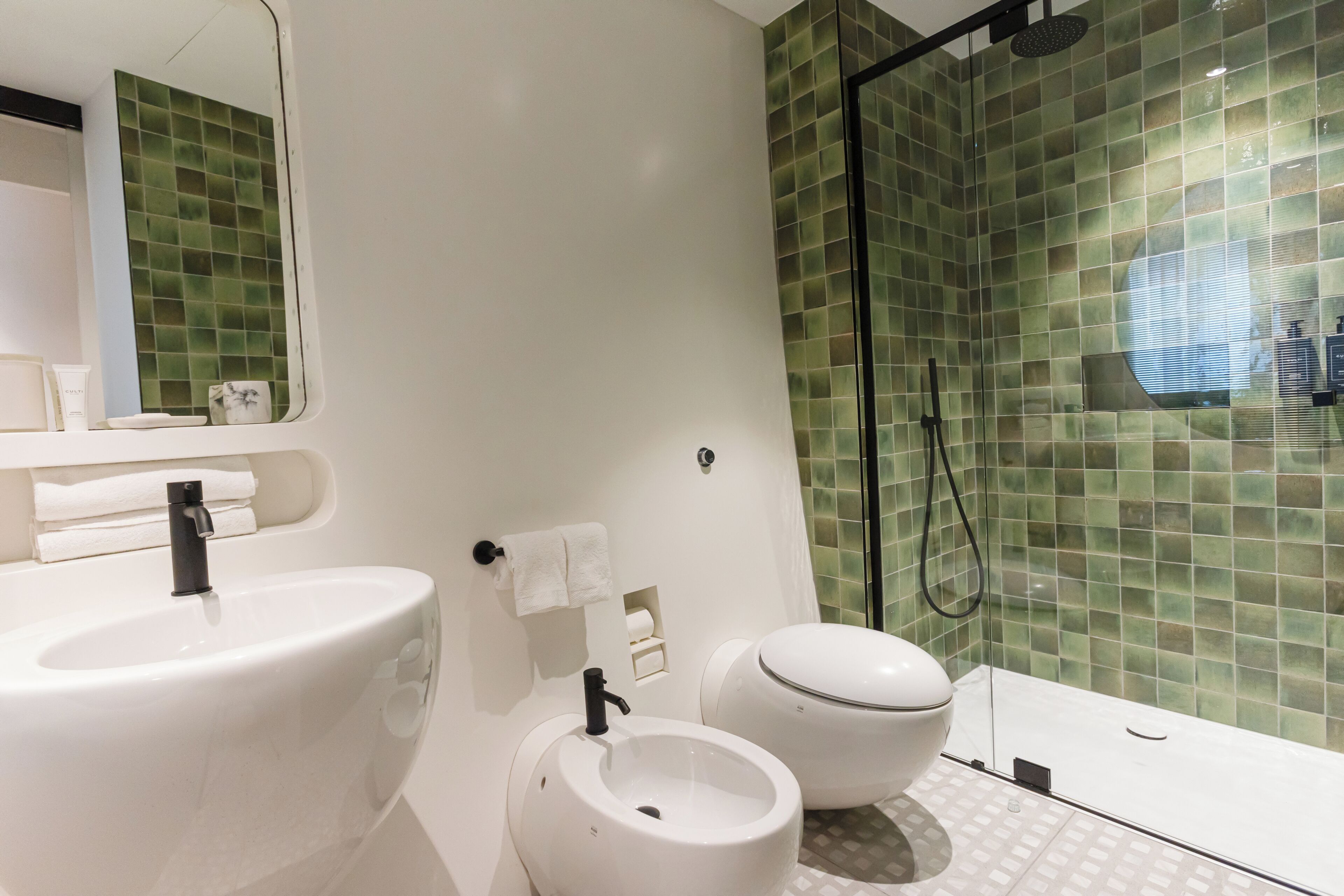 A modern bathroom with a white sink, toilet, and glass-enclosed shower.