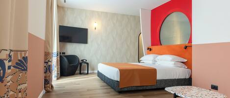 A modern hotel room with a bed, a small table, a TV mounted on the wall, and a patterned wall.