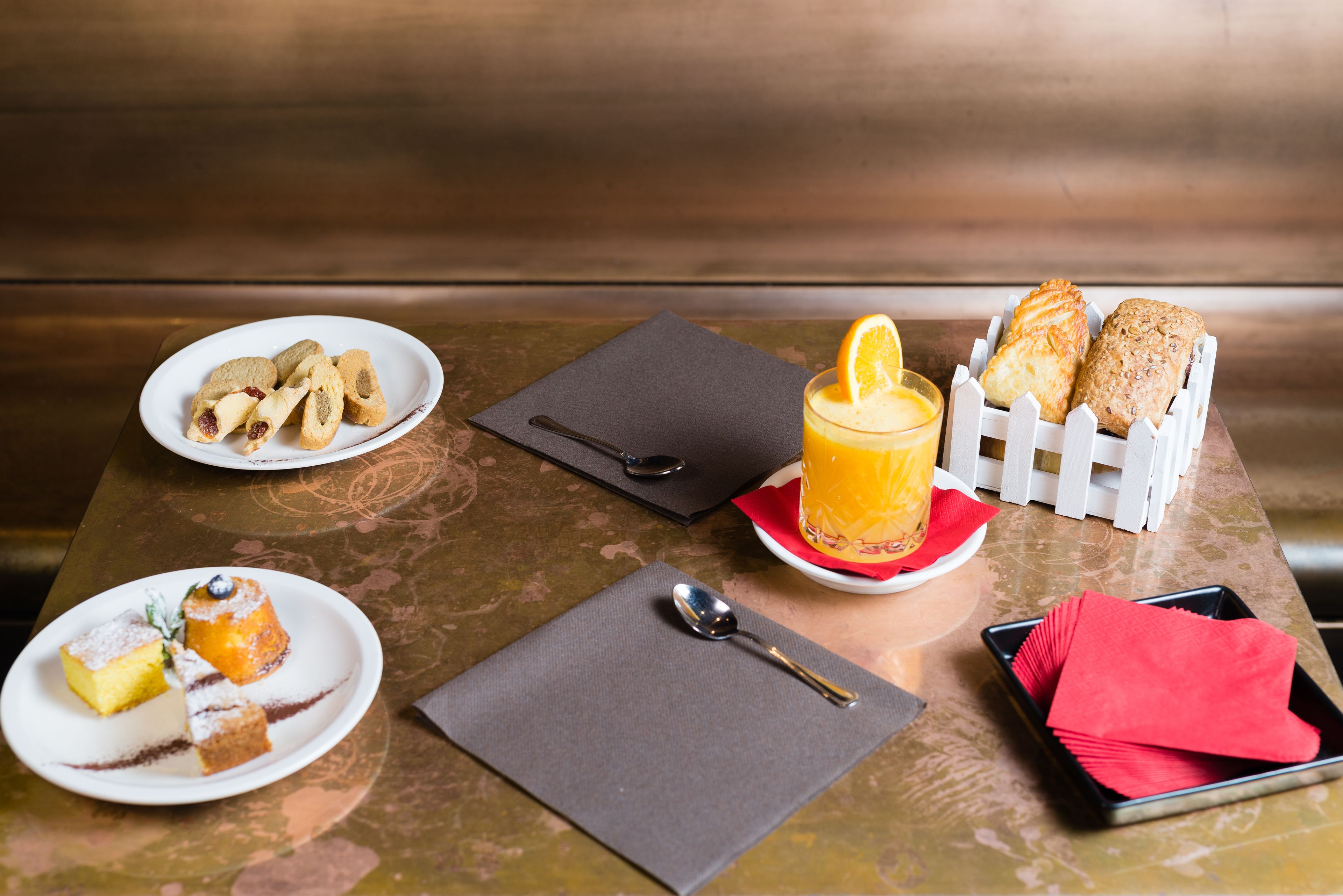 A table with various breakfast items including pastries, a glass of orange juice, and a plate of desserts.