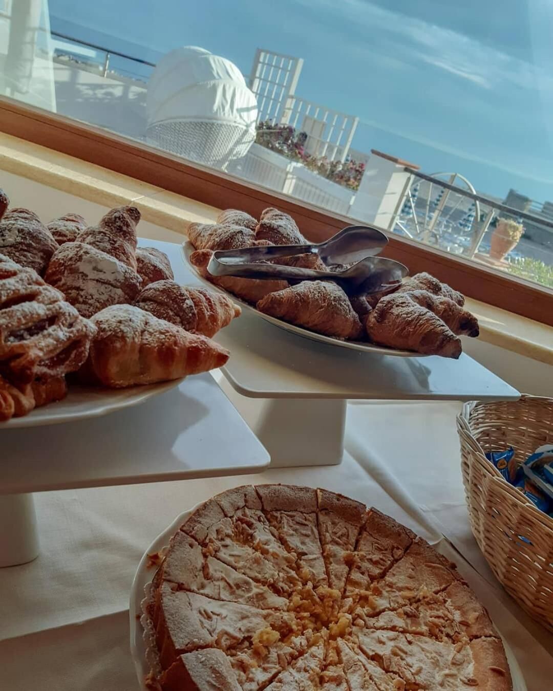 Una mesa de buffet con pastelería y un pastel, con vista a un balcón y asientos al aire libre.
