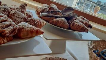 Una mesa de buffet con pastelería y un pastel, con vista a un balcón y asientos al aire libre.