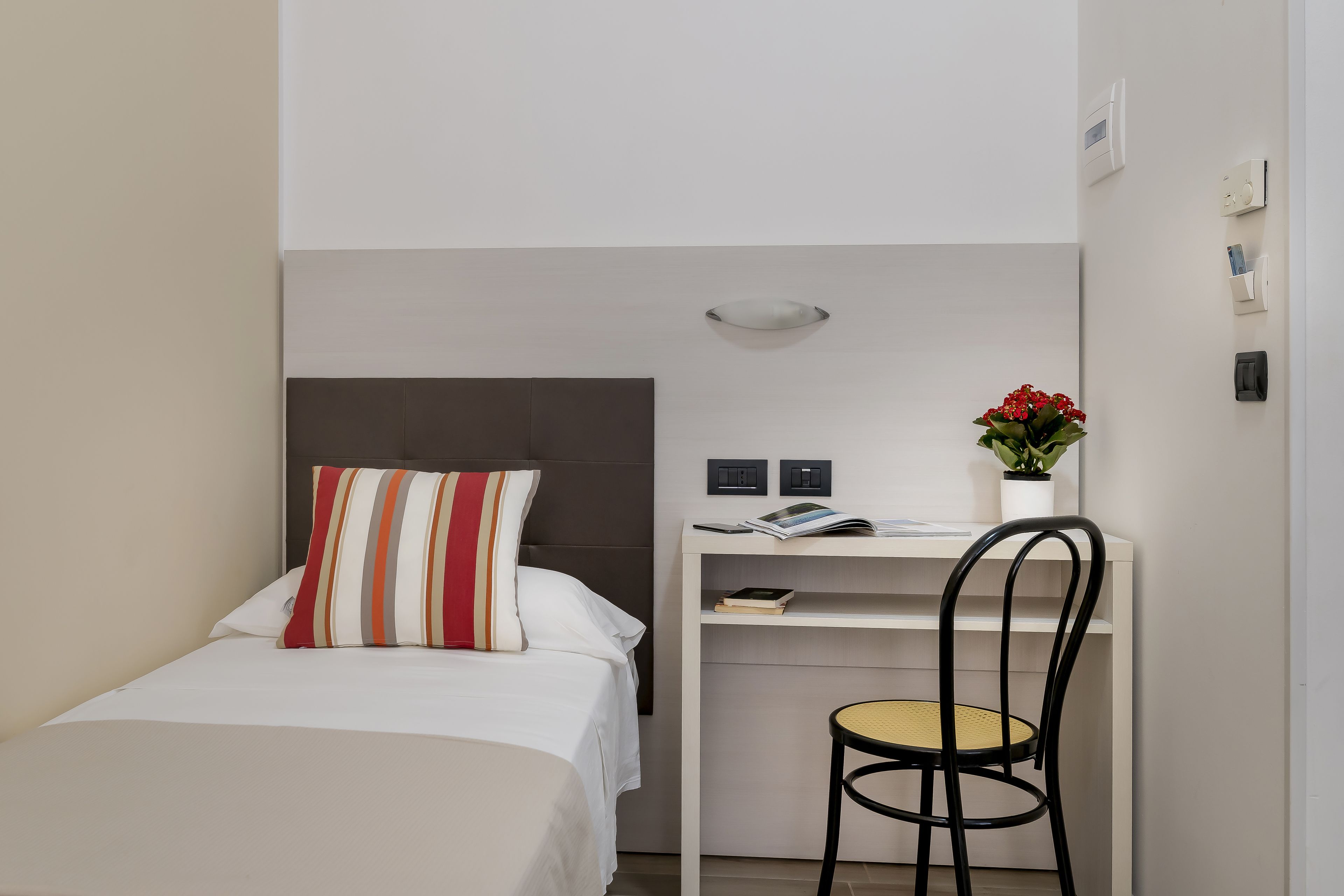 Habitación de hotel pequeña con cama, escritorio y silla.