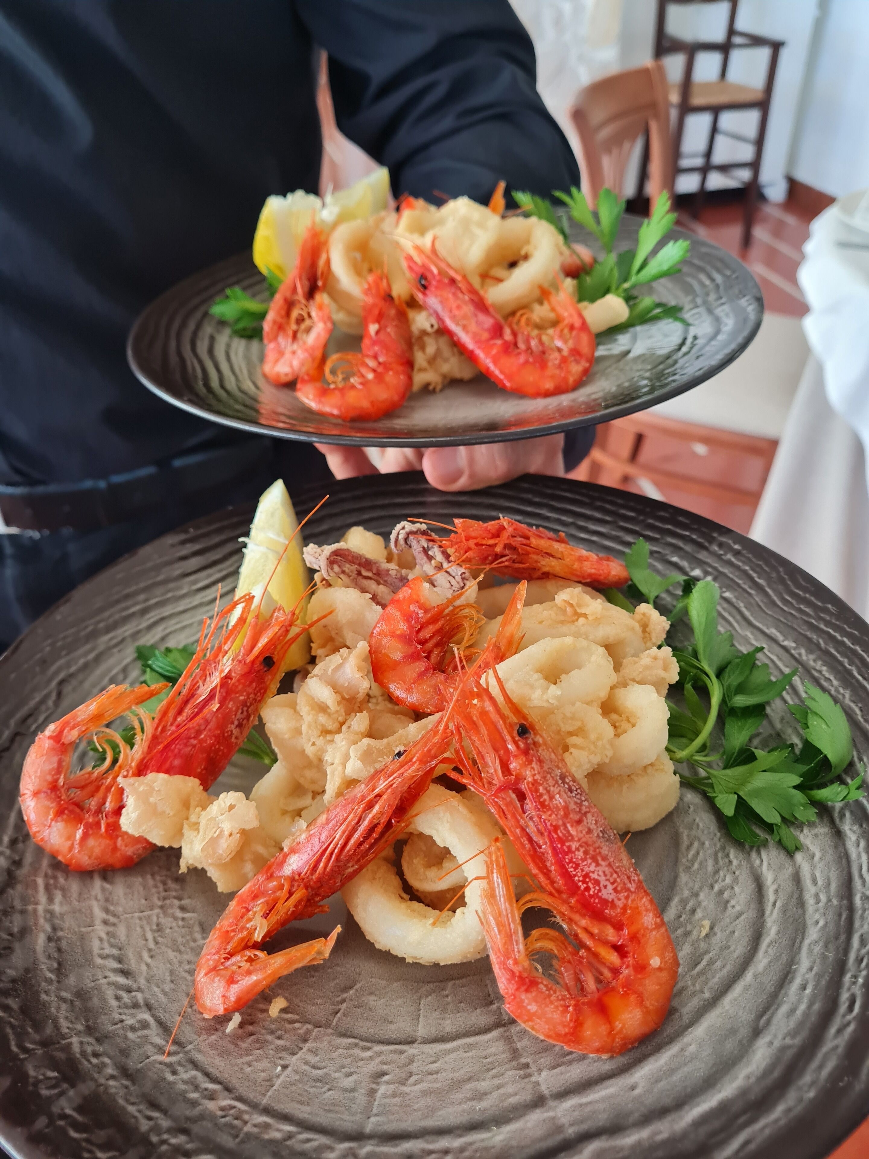 A person holding a plate with shrimp and seafood.