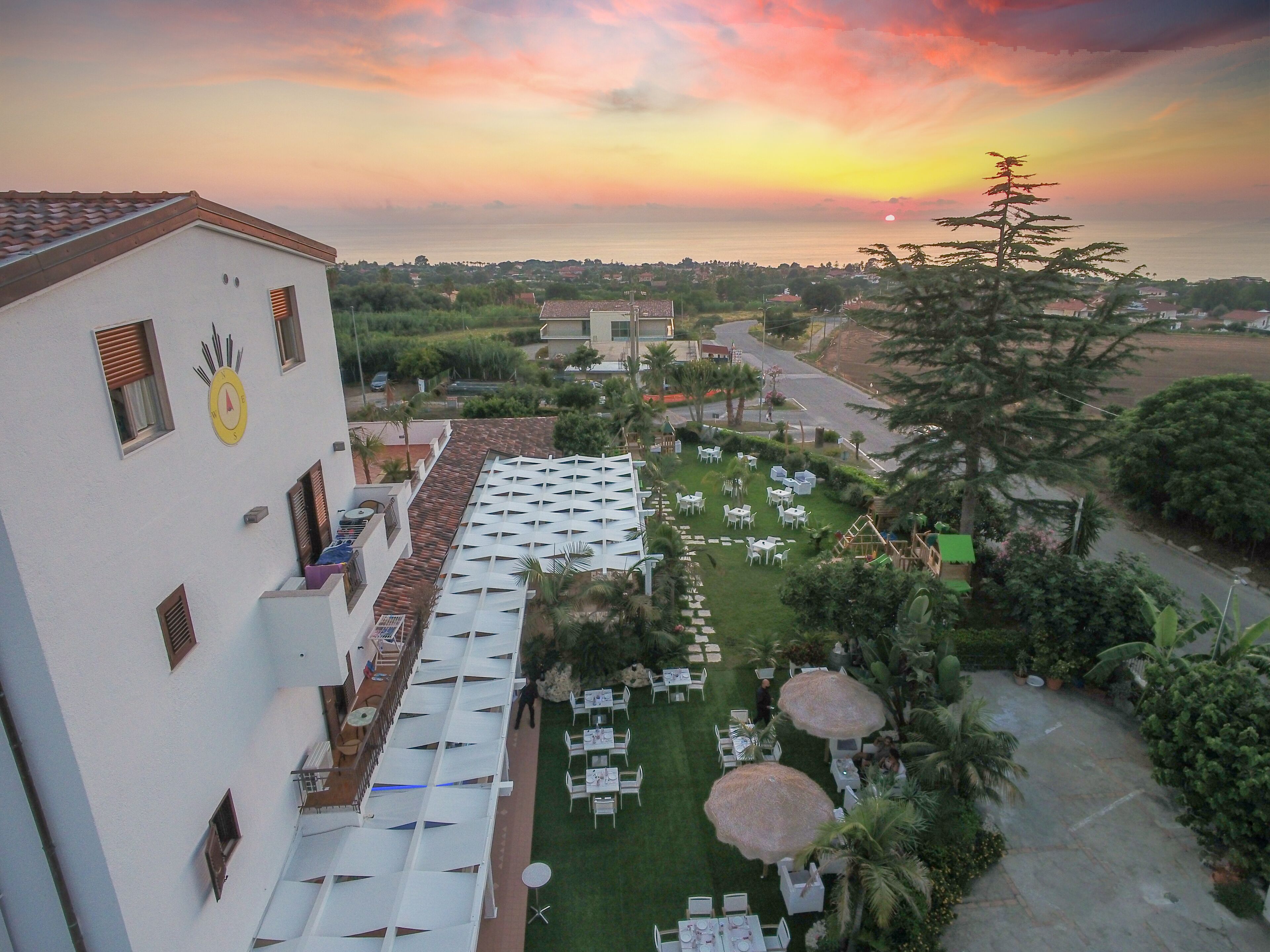 A hotel with outdoor seating and a view of the sunset.