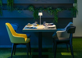 Un coin repas avec une table dressée pour deux personnes, comprenant des chaises modernes et une table au design minimaliste.