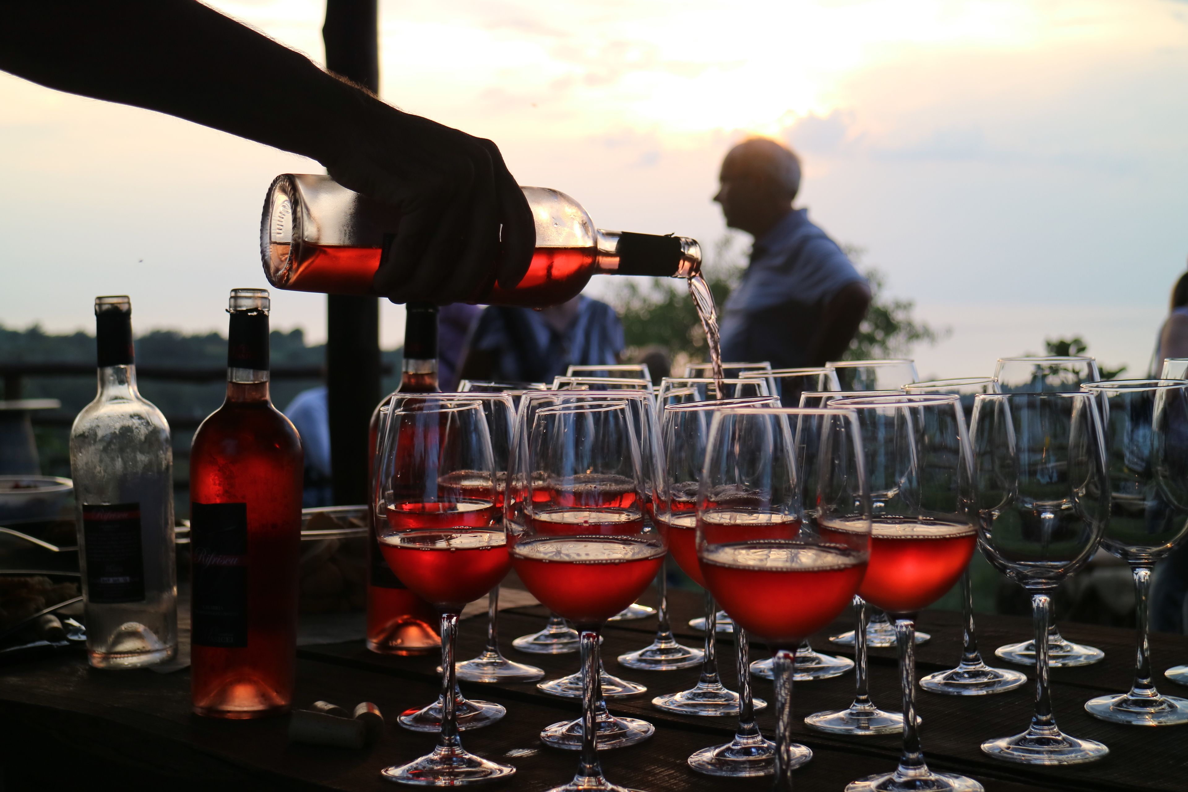 A bar setting with multiple wine glasses and bottles, likely for a social event.