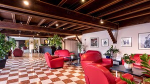 A lobby with red leather sofas, a checkered floor, wooden beams, and potted plants. - Best Western Titian Inn Hotel Treviso (Silea)