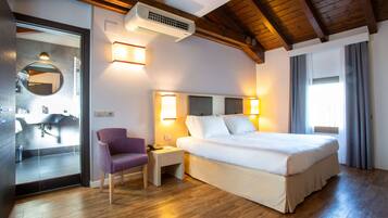 Ein Hotelzimmer mit Bett, Nachttisch, Stuhl und angrenzendem Badezimmer.