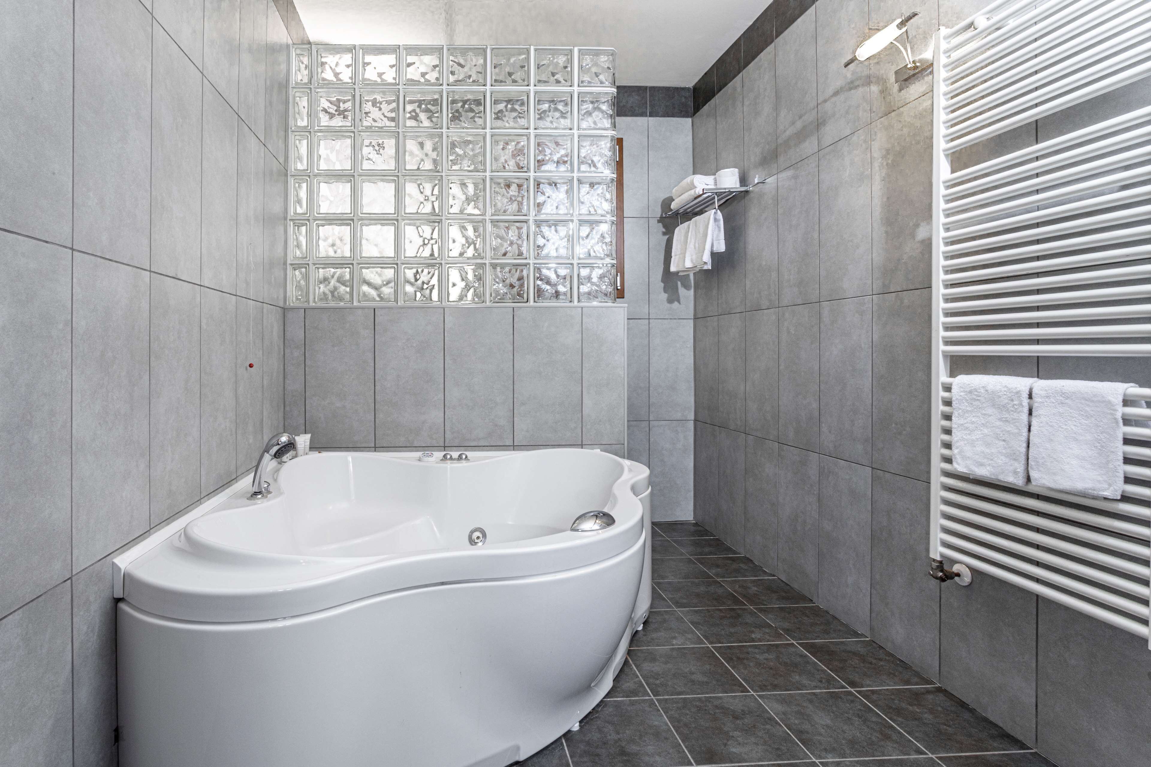 A modern bathroom with a freestanding bathtub, tiled walls, and a towel rack.