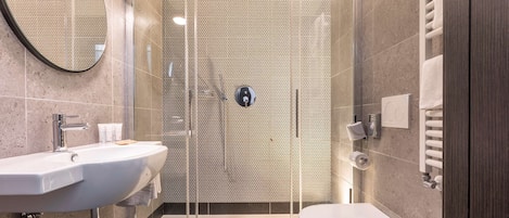 A modern bathroom with a glass-enclosed shower, a sink, and a toilet.