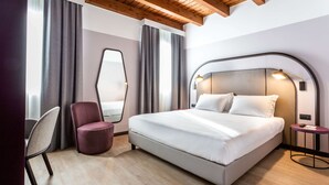 A modern hotel room with a large bed, a chair, a round table, and a mirror. - Best Western Titian Inn Hotel Treviso (Silea)