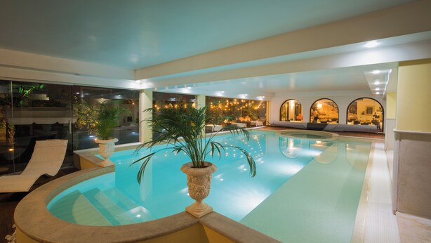 Une piscine avec des chaises longues et des plantes en pot.