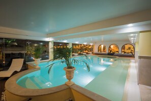 A swimming pool with lounge chairs and potted plants.