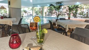Un espace repas avec des tables, des chaises et une vue sur une piscine.