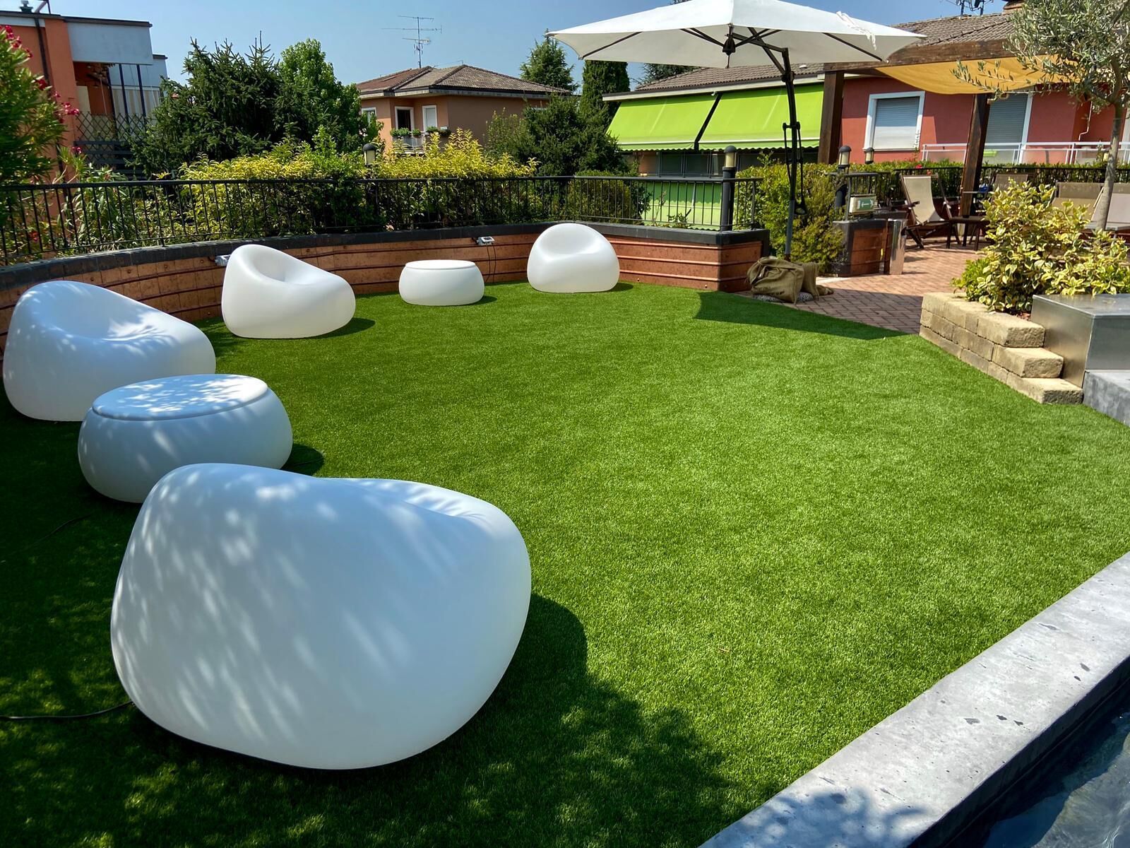 Eine Dachterrasse mit künstlichem Rasen und mehreren weißen, runden Sitzbereichen.