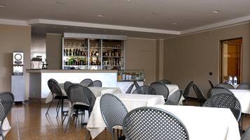 Ein Restaurant mit Tischen und Stühlen, eine Bar mit Regalen voller Flaschen und ein Kühlschrank.