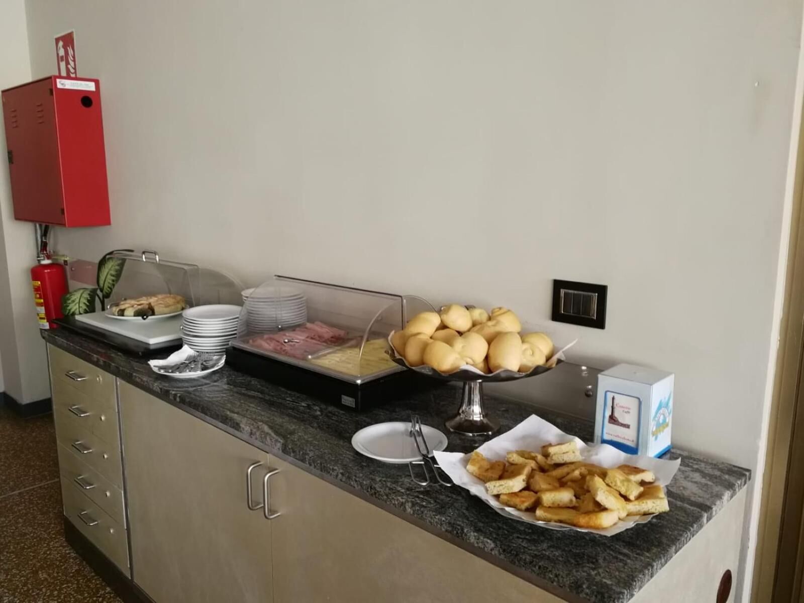 Disposição de buffet com diversos alimentos, incluindo pão, pastelaria e uma bandeja de batatas fritas.