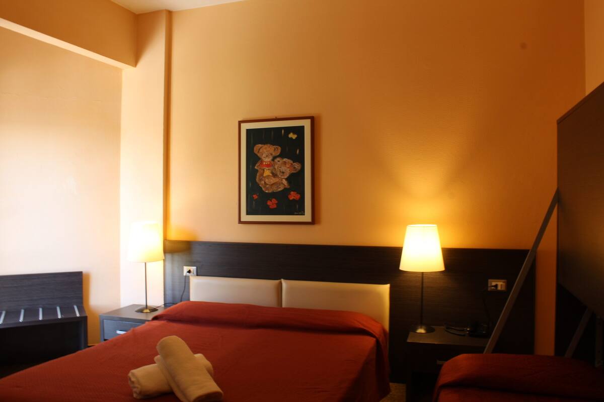 A hotel room with a bed, two bedside tables, a lamp, and a framed picture on the wall.