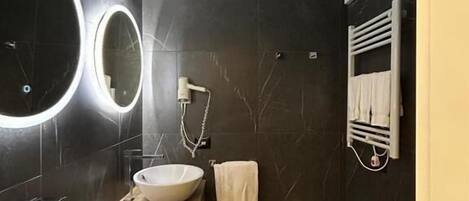 Un baño moderno con un espejo grande, dos lavamanos, un inodoro y un perchero para toallas.