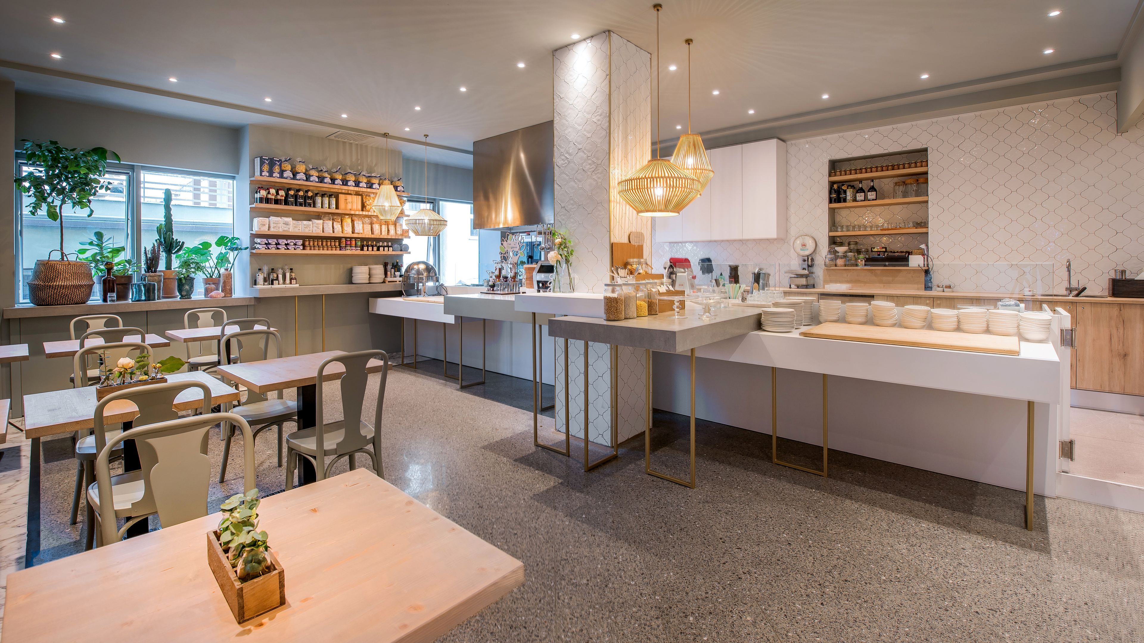 A modern restaurant with a central bar area, seating arrangements, and a variety of food and drink items displayed on shelves.