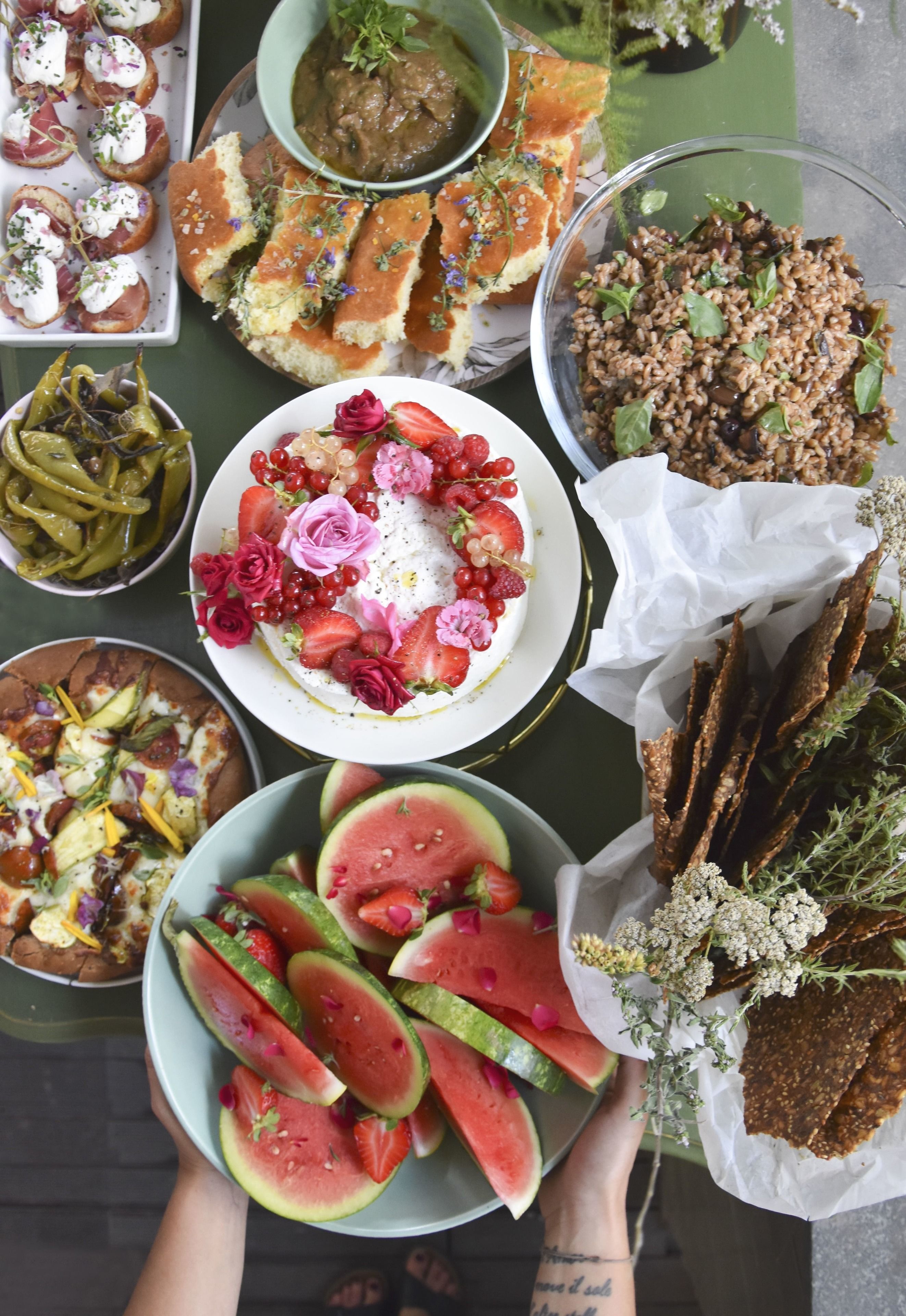 A variety of food items including watermelon slices, bread, and a plate with strawberries and flowers.