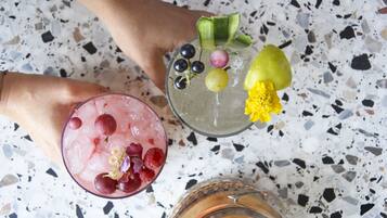 Two cocktails with garnishes on a terrazzo floor.