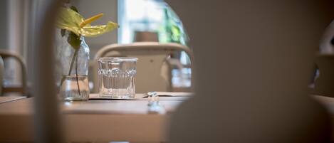 Una mesa con un vaso de vidrio transparente y un pequeño florero con una sola flor.