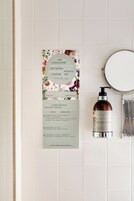 Un bagno con uno specchio, una bottiglia di Rosa Ranciughetti e un cartello con consigli per l'ambiente.