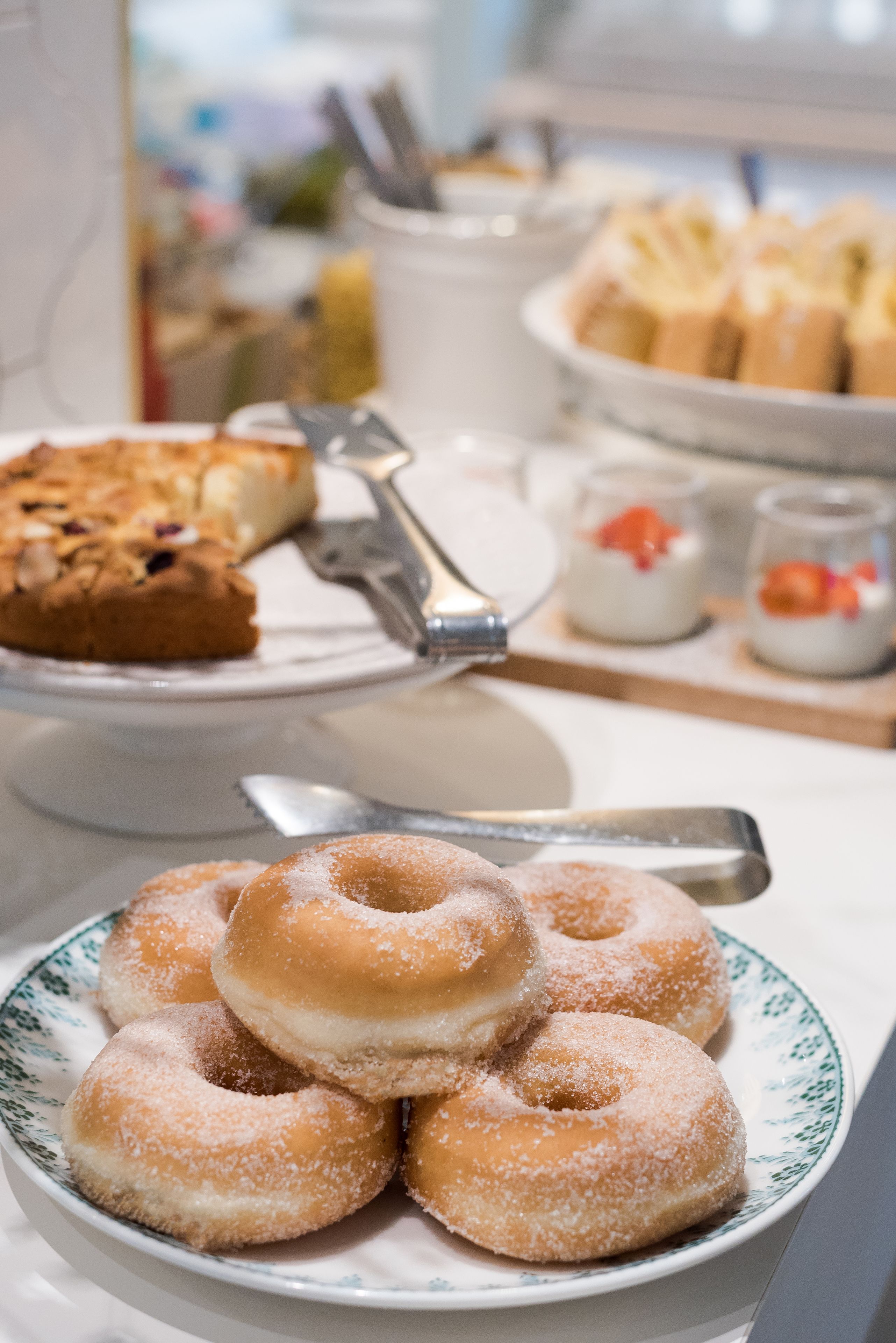 Ein Buffet mit verschiedenen Desserts, darunter ein Teller mit Donuts und eine Torte.