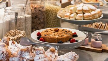 Ein reichhaltiges Buffet mit einer Auswahl an Speisen, darunter Gebäck, Früchten und Desserts.