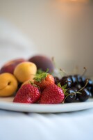 Un piatto di frutta fresca con fragole, pesche e ciliegie.