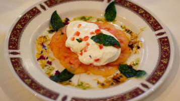 A plate of food with a creamy topping, tomatoes, and green leaves.