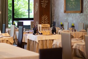 Uma área de refeições com mesas postas para uma refeição, com seleção de vinhos e centros de mesa com velas.