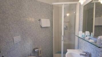 A bathroom with a toilet, bidet, sink, and a glass-enclosed shower.