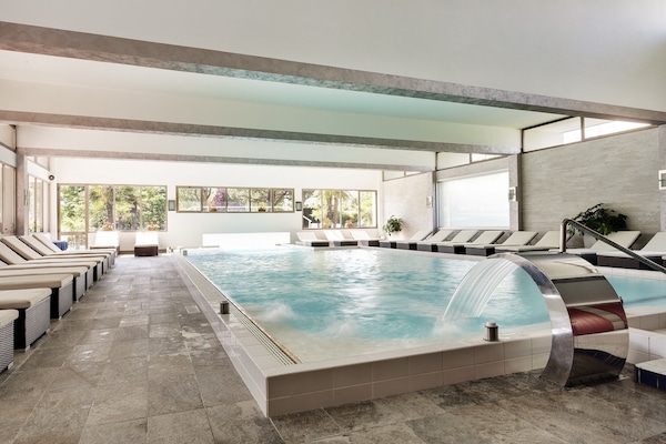 Alberca techada, alberca al aire libre y sombrillas en la alberca