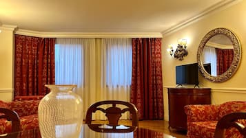 Una camera d'albergo con un vaso grande, due divani, una TV e uno specchio a parete.