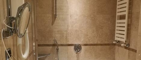 Ein modernes Badezimmer mit einer Badewanne, zwei Toiletten, einer Dusche und einem Händetrockner.