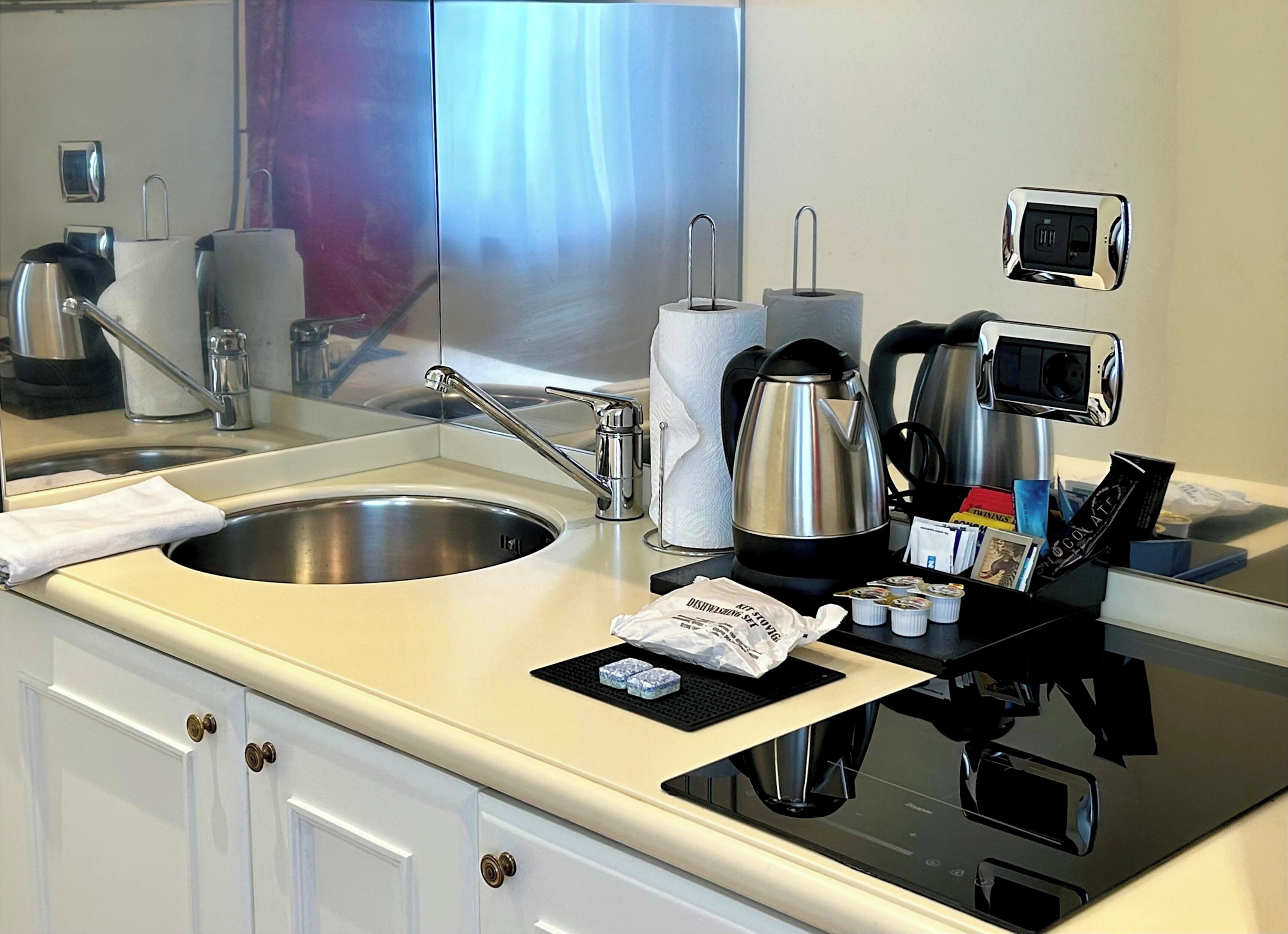 Een hotelbadkamer met een wastafel, spiegel, zeepdispenser en een koffieapparaat.