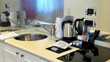Een hotelbadkamer met een wastafel, spiegel, zeepdispenser en een koffieapparaat.