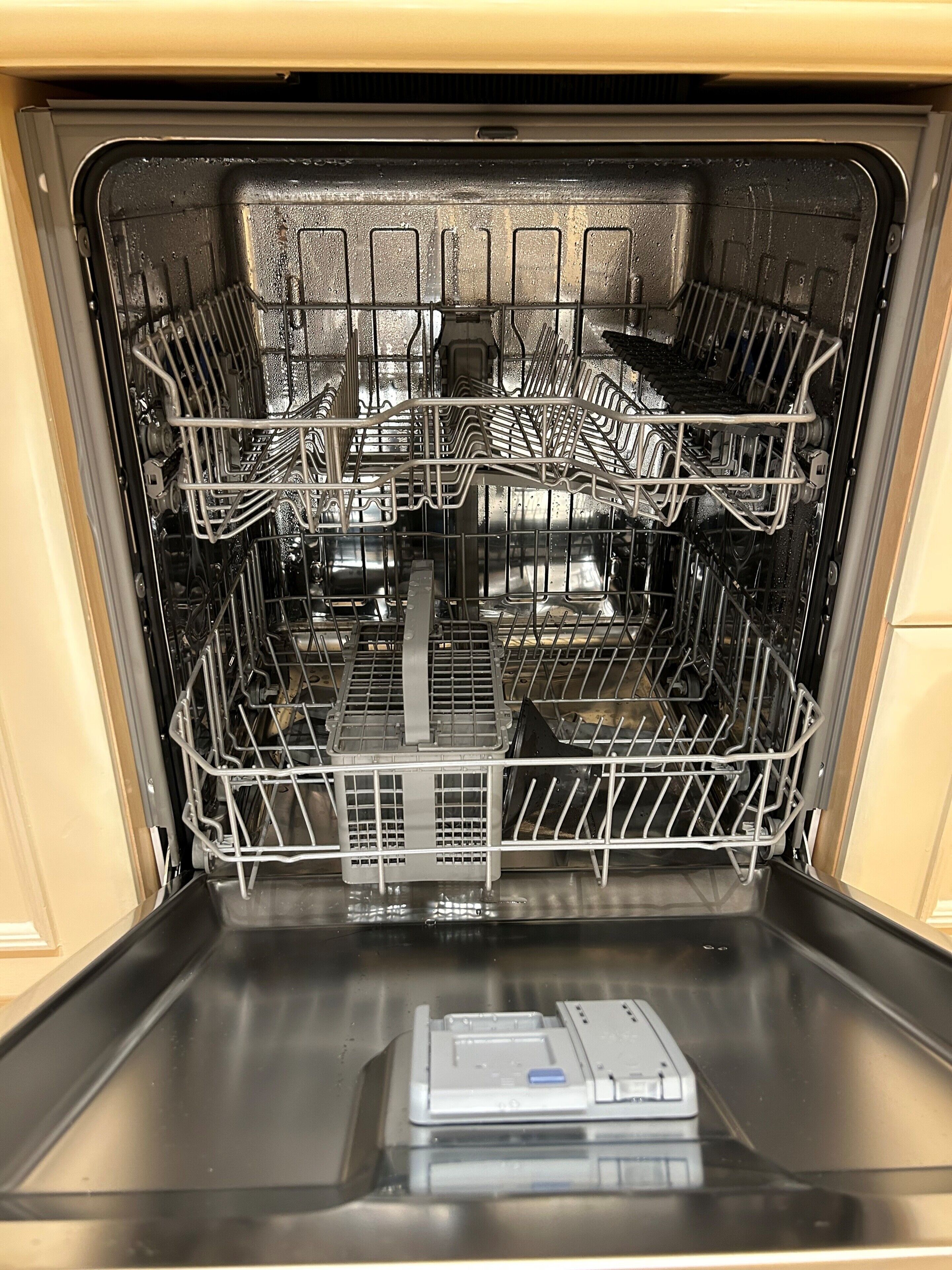 An open dishwasher with multiple racks and a control panel.