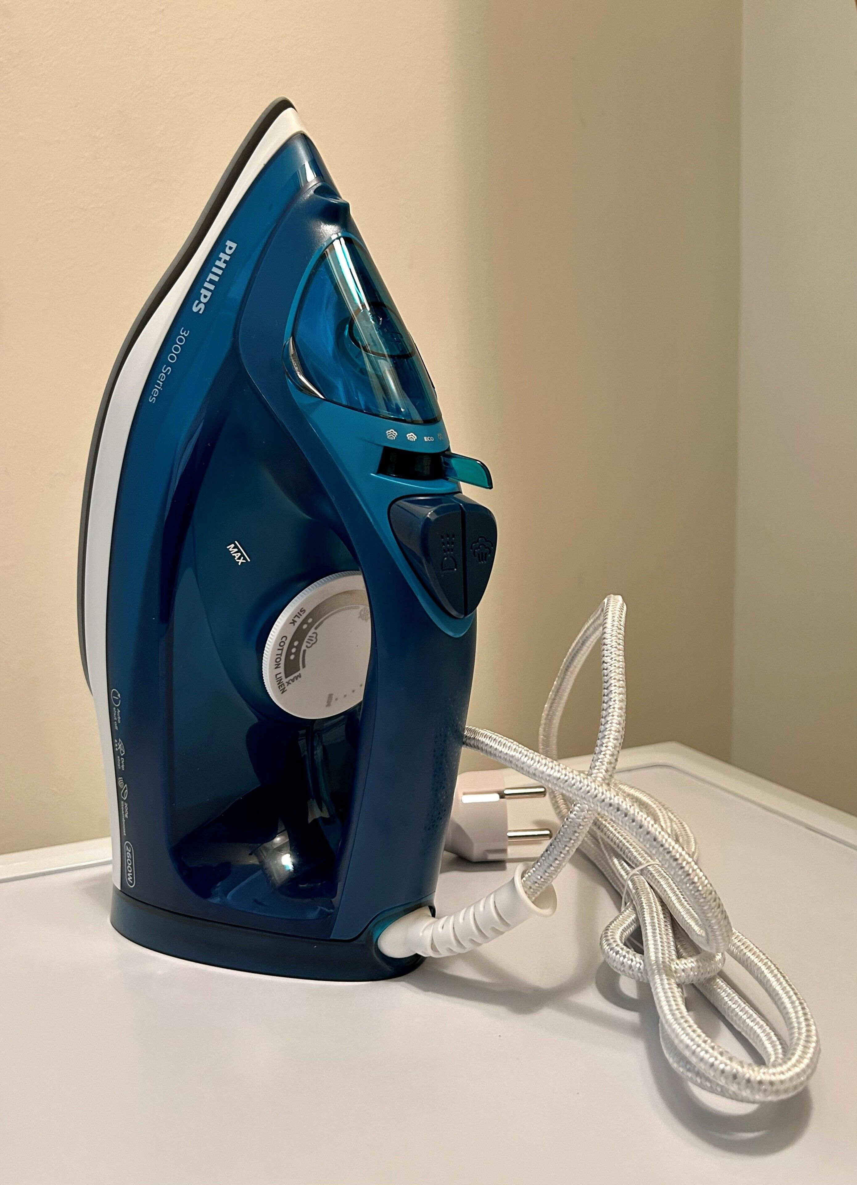 Un cepillo azul con cable, un enchufe y una pared.