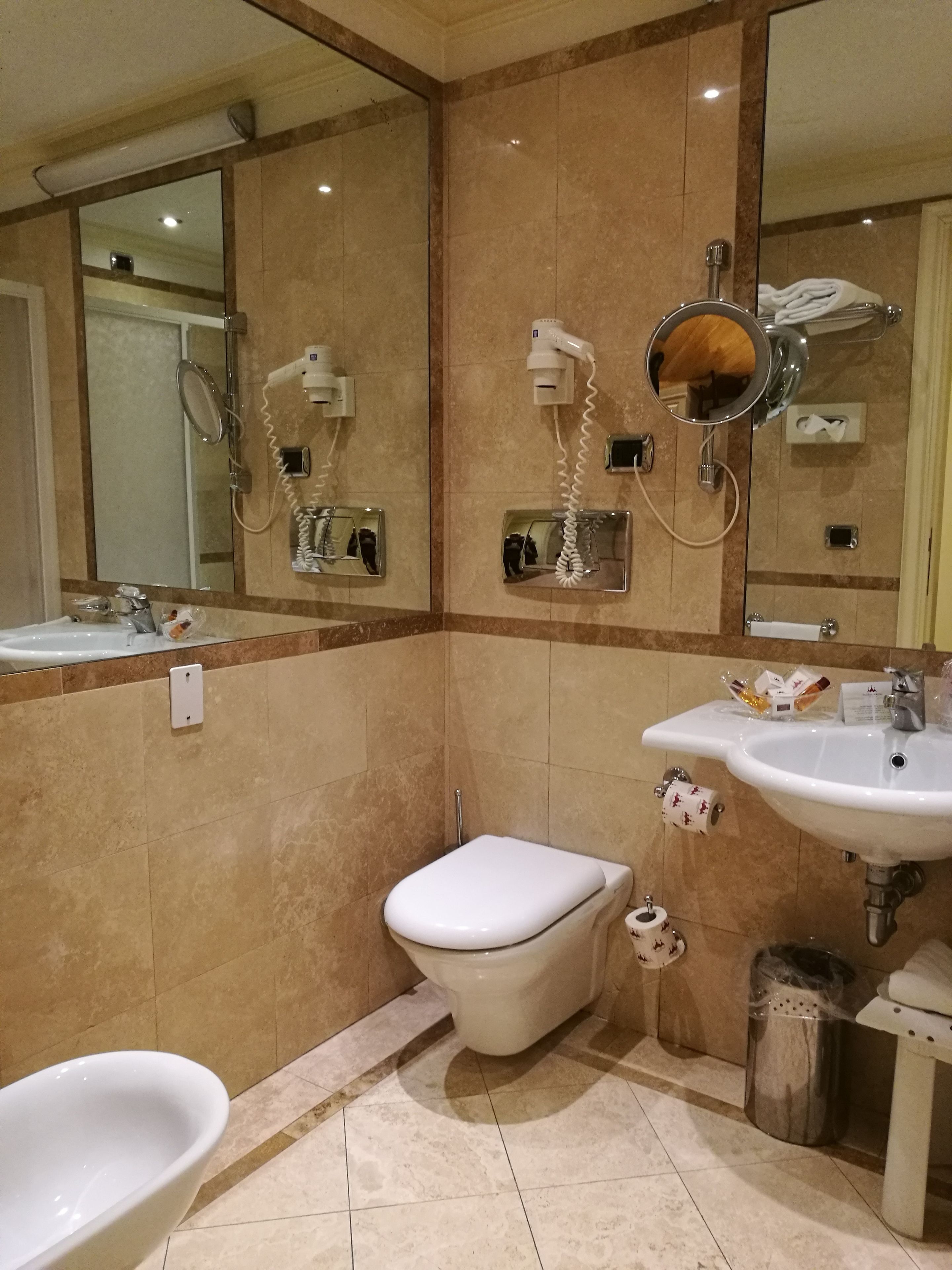 Un baño con inodoro, bidé y dos lavamanos.