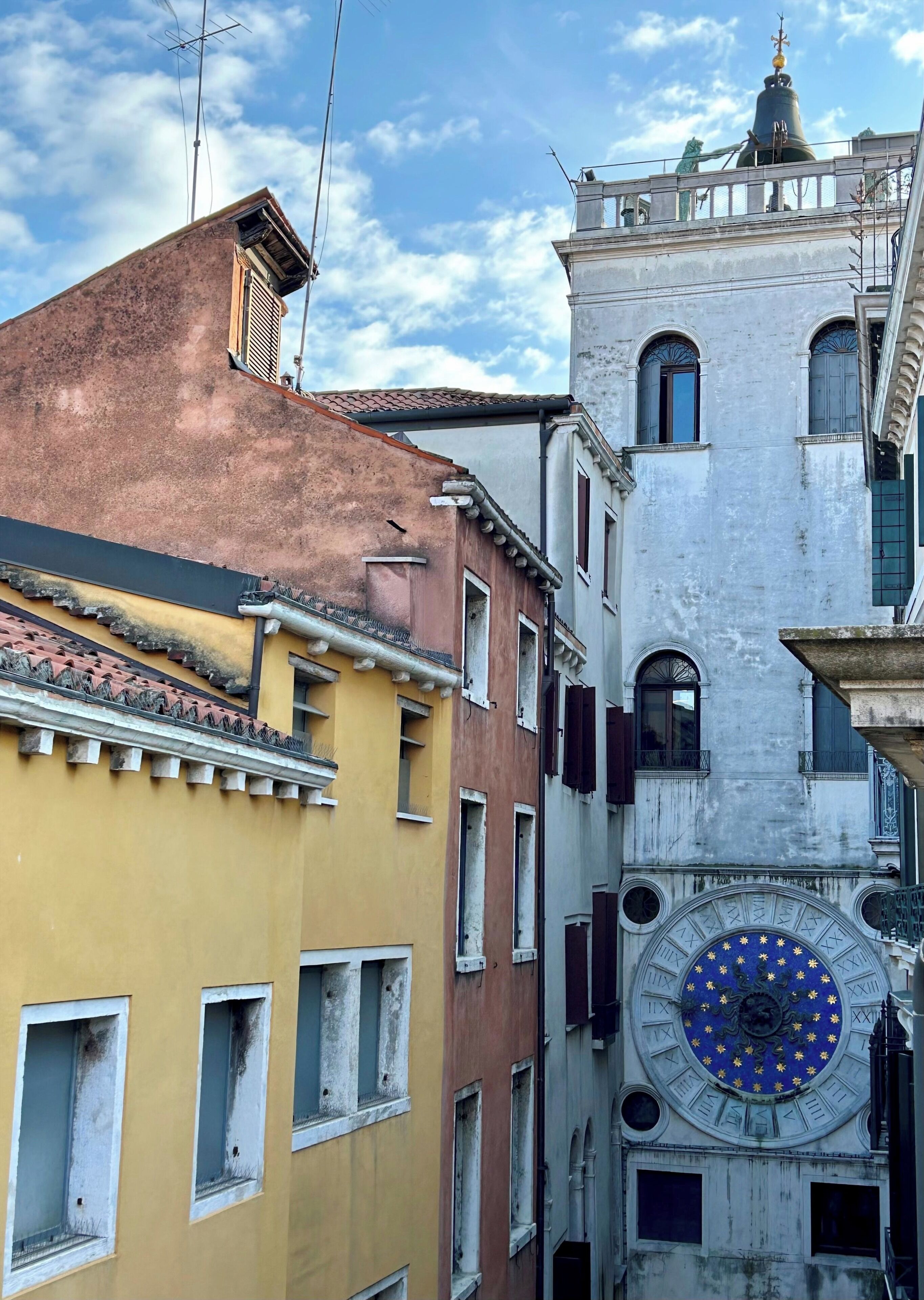 Un vicolo stretto con edifici dall'architettura tradizionale, tra cui un campanile con quadrante blu e oro.