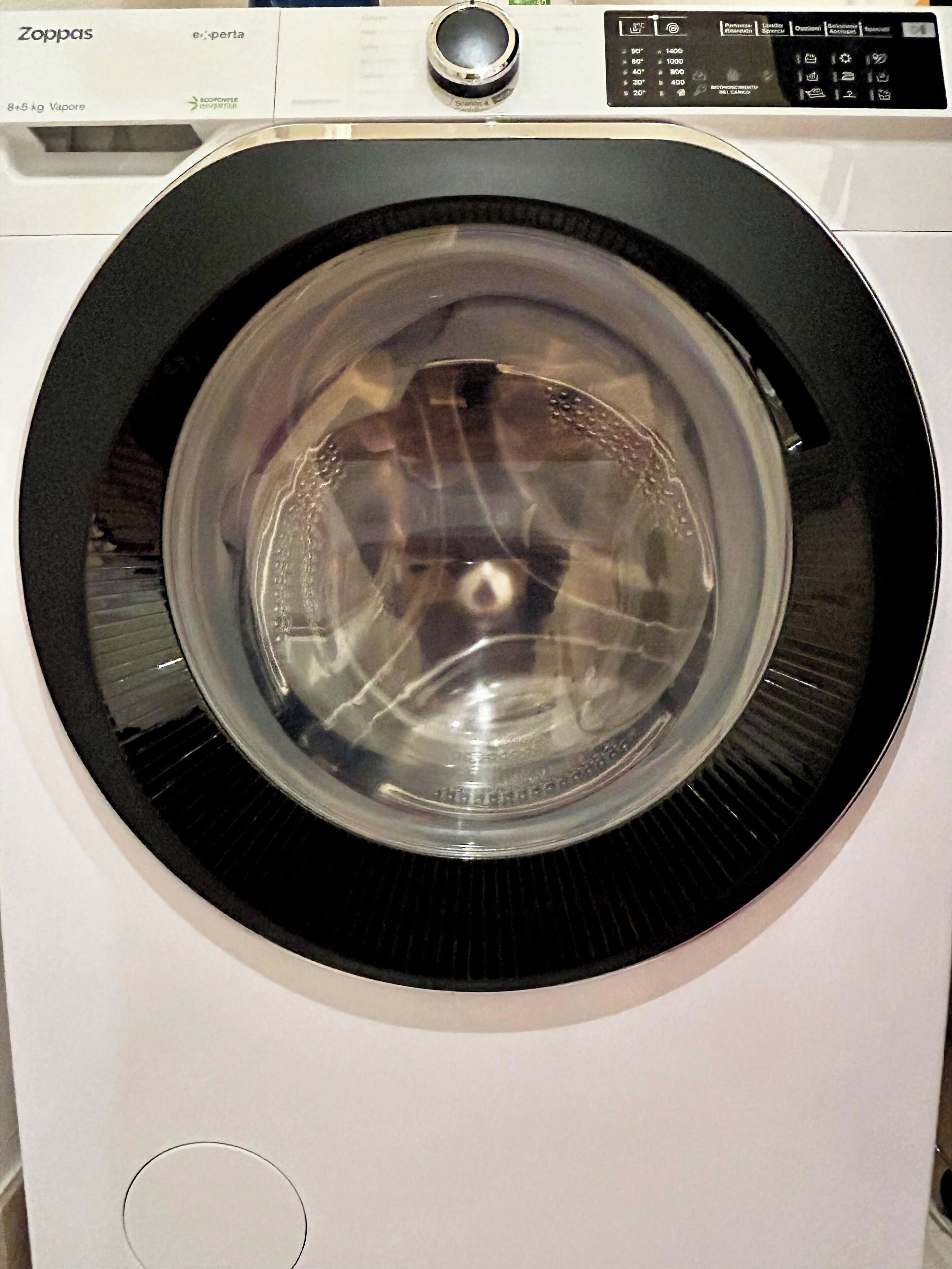 A front view of a Zoppas washing machine with a transparent door, control panel, and a circular door design.